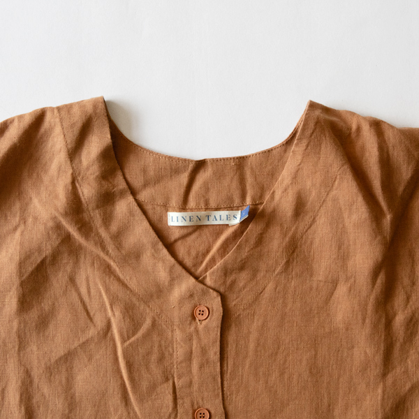ノーカラーのVネックで、首元にはLINEN TALESのタグが付いています