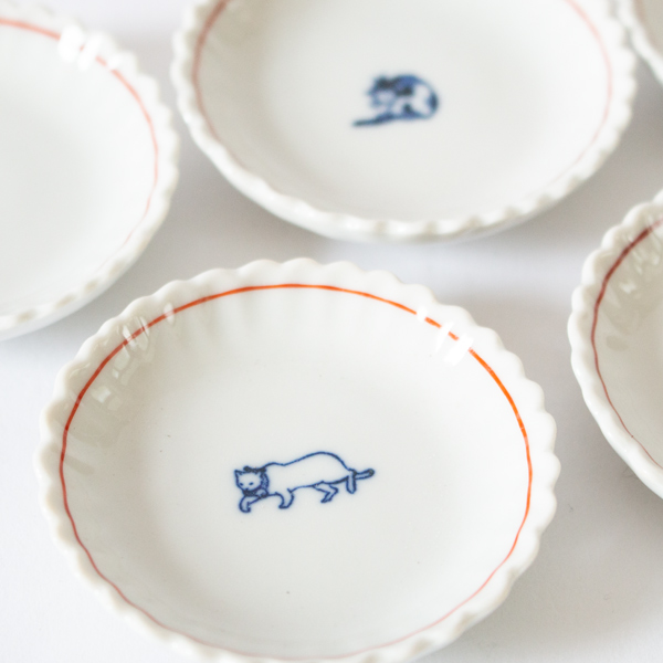 余白のある白磁に、のびやかな筆致で描かれた猫たち